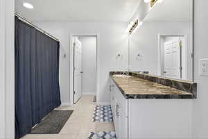Bathroom featuring vanity, light tile patterned floors, and a shower with shower curtain