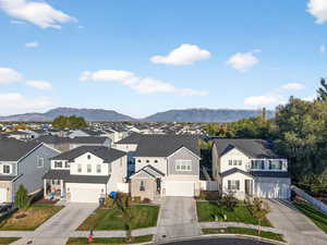 View of front of property featuring driveway, a mountain view, a residential view, board and batten siding, and a garage