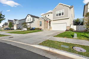 Traditional-style house with concrete driveway, board and batten siding, a residential view, and an attached garage