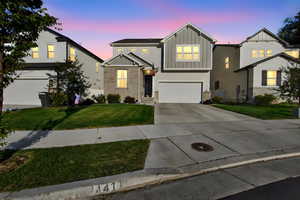 View of front facade with board and batten siding, concrete driveway, a front yard, a garage, and brick siding