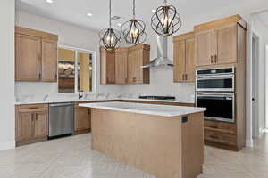 Kitchen featuring hanging light fixtures, stainless steel appliances, light stone countertops, a center island, and recessed lighting