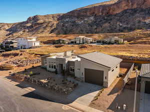 View of front facade featuring stone siding, stucco siding, a mountain view, concrete driveway, and a residential view