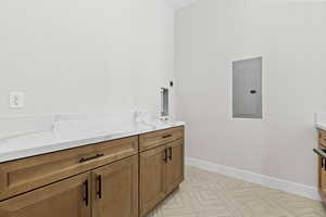 Laundry area with electric panel and cabinet space