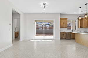 Kitchen with brown cabinetry, a chandelier, hanging light fixtures, stainless steel dishwasher, and recessed lighting