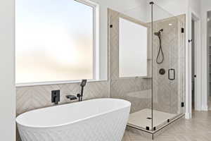 Bathroom with a freestanding bath, a stall shower, healthy amount of natural light, and tile walls