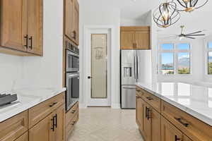Kitchen with a chandelier, stainless steel appliances, hanging light fixtures, and brown cabinetry