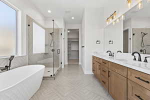 Bathroom featuring a stall shower, a freestanding bath, a spacious closet, double vanity, and recessed lighting