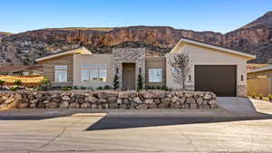 Modern home with stone siding, driveway, and a mountain view