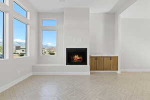 Unfurnished living room featuring a lit fireplace, healthy amount of natural light, and a mountain view