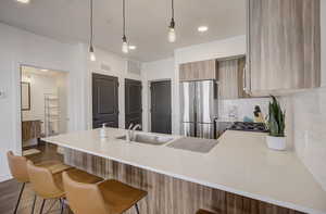 Kitchen featuring a peninsula, modern cabinets, pendant lighting, freestanding refrigerator, and decorative backsplash