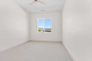 Unfurnished room with a mountain view, light carpet, and ceiling fan