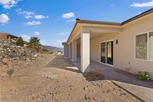 View of side of property featuring stucco siding, a mountain view, and a patio area