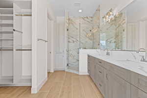 Bathroom featuring a marble finish shower, double vanity, wood tiled floors, and recessed lighting