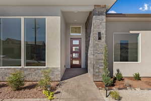 Doorway to property with stone siding and stucco siding