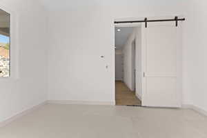 Empty room with a barn door, light colored carpet, and recessed lighting