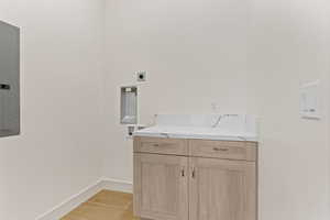 Laundry area with electric panel, cabinet space, and washer hookup