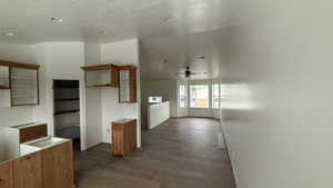 Kitchen with ceiling fan, dark wood-type flooring, wood finish cabinets, and a textured ceiling