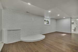 Bathroom featuring brick wall, light wood-style floors, and recessed lighting