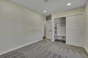 Unfurnished bedroom featuring light carpet, a closet, and recessed lighting