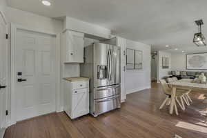 Kitchen with recessed lighting, white cabinets, stainless steel refrigerator with ice dispenser, open floor plan, and light wood finished floors