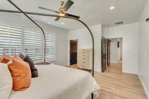 Bedroom with recessed lighting, light wood-style flooring, ceiling fan, wooden walls, and a textured ceiling