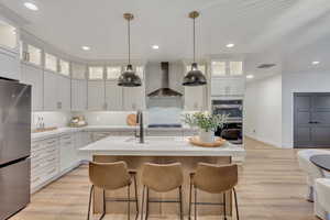 Kitchen featuring glass insert cabinets, appliances with stainless steel finishes, light wood-style floors, white cabinets, and recessed lighting