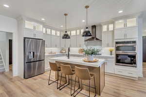 Kitchen featuring stainless steel appliances, backsplash, wall chimney exhaust hood, recessed lighting, and white cabinets