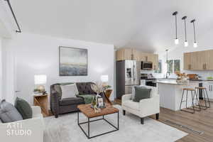 Living room featuring vaulted ceiling and light wood-style floors