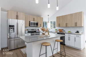 Kitchen with stainless steel appliances, a breakfast bar, pendant lighting, light wood-style floors, and high vaulted ceiling
