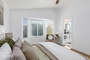 Bedroom featuring wood finished floors, vaulted ceiling, a ceiling fan, and connected bathroom