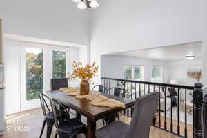 Dining space featuring light wood-type flooring, a towering ceiling, and a chandelier