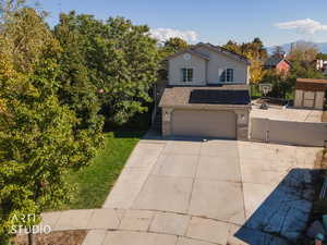 Traditional-style home featuring roof mounted solar panels, a gate, concrete driveway, roof with shingles, and an attached garage