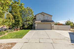View of front facade featuring a gate, solar panels, concrete driveway, an attached garage, and stone siding