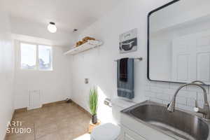 Washroom with light tile patterned flooring and hookup for a washing machine