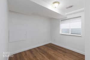 Spare room with baseboards and dark wood-style floors