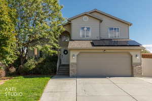 Traditional home featuring driveway, a garage, and solar panels