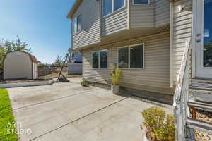 Rear view of house featuring a shed and a patio area