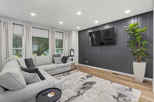 Living area with recessed lighting, light wood finished floors, and wood walls