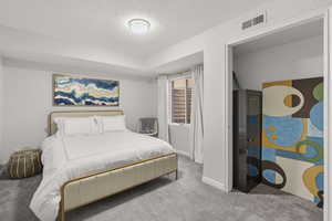 Carpeted bedroom featuring a textured wall and a textured ceiling