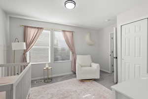 Bedroom featuring a crib, light colored carpet, and a closet