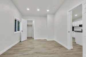 Unfurnished bedroom with a spacious closet, recessed lighting, and light wood-style flooring