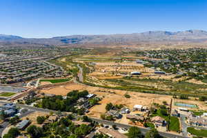 Aerial view of property and surrounding area featuring nearby suburban area and mountains