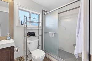 Bathroom featuring a textured ceiling, a shower stall, and vanity
