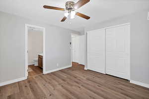 Unfurnished bedroom featuring light wood-type flooring, a closet, ceiling fan, and ensuite bathroom