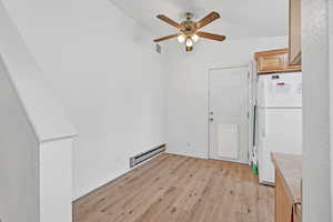 Unfurnished dining area with light wood-style floors, baseboard heating, and ceiling fan