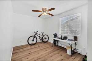 Office with light wood-type flooring, ceiling fan, and a baseboard heating unit