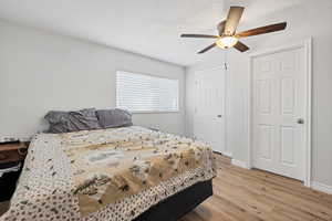 Bedroom with a textured ceiling, light wood-style flooring, and ceiling fan