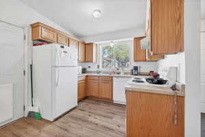 Kitchen featuring light countertops, white appliances, light wood-style flooring, and ventilation hood