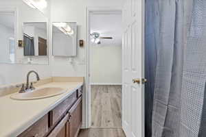 Full bath with a shower with shower curtain, vanity, light wood-style floors, and ceiling fan
