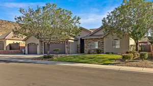View of front facade featuring stucco siding, driveway, stone siding, a garage, and a tiled roof
